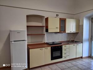 una cucina con armadietti bianchi e frigorifero bianco di Casa Vacanze la Paloma a Peschici