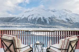 a balcony with two chairs and a table and a mountain at Badrutt's Palace Hotel St Moritz in St. Moritz