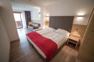 sypialnia z dużym łóżkiem i czerwonym kocem w obiekcie Olimpionico Hotel w mieście Castello-Molina di Fiemme