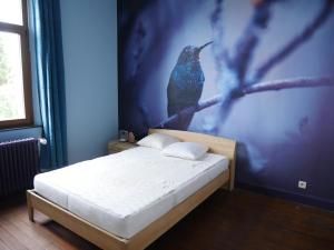 1 dormitorio con 1 cama y una pintura de un pájaro en Le nichoir d’hirondelles en Tintigny