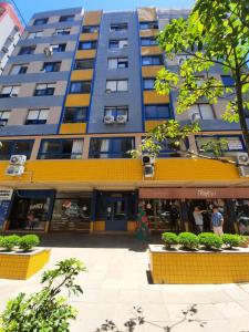 un edificio alto azul con adornos amarillos junto a una calle en Apartamento 308, Marina, Centro - Torres - RS, en Torres