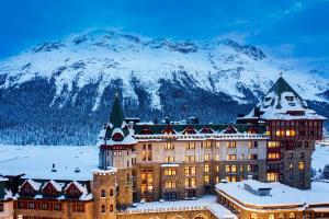 a hotel in the snow in front of a mountain at Badrutt's Palace Hotel St Moritz in St. Moritz