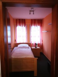 a bedroom with a bed and two windows at Pension Zum Angestellten in Porta Westfalica