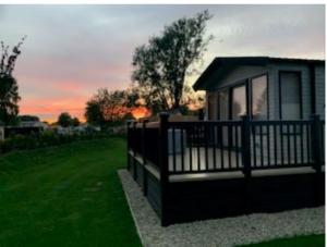 a small cabin with a fence in the grass at Lavender Lodge in South Cerney