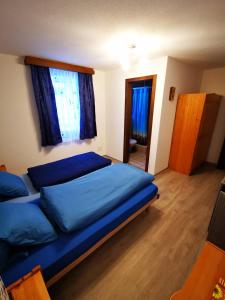 a bedroom with a bed with blue sheets and windows at Sunshine in Saas-Grund