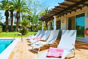 a row of lounge chairs next to a swimming pool at Villa Bogota by Algarve Vacation in Albufeira