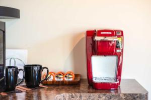 a red toaster sitting on a counter with two cups at Cozy Volcano Studio with Phenomenal Rainforest Views! in Mountain View