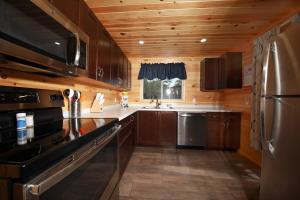 a kitchen with wooden cabinets and a stainless steel refrigerator at Cavendish Maples Cottages in Cavendish