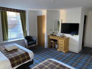 a hotel room with a bed and a desk with a television at Royal Dunkeld Hotel in Dunkeld