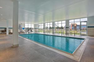 a large swimming pool in a building with tables and chairs at Hyatt Place at Wichita State University in Wichita