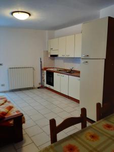 una cocina con electrodomésticos blancos, mesa y sillas en Alloggi Il Rododendro, en Bagni di Vinadio