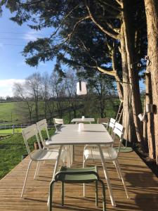 a white table and chairs on a wooden deck at La Canopée du Mont in Saint-Georges-de-Reintembault