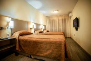 um quarto de hotel com duas camas e uma televisão em Punta Trouville Hotel em Montevidéu