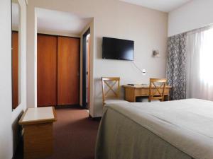 um quarto de hotel com uma cama, uma secretária e uma televisão em Hotel Libertador em Trelew