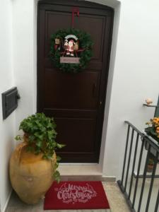 uma coroa de Natal numa porta com uma planta à frente em B&B Il RE em Castellaneta