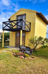 a yellow house with a sign in front of it at Complejo Vidas del Mar in Punta Del Diablo