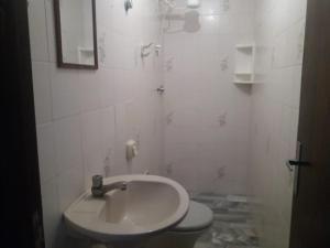 a white bathroom with a sink and a toilet at Sobrado Guaratuba in Guaratuba