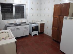 a kitchen with a stove and a sink and a refrigerator at Sobrado Guaratuba in Guaratuba