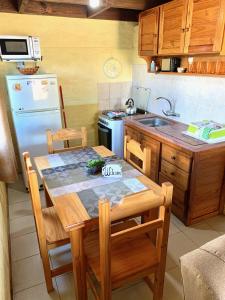 cocina con mesa, fregadero y nevera en Complejo Vidas del Mar, en Punta del Diablo