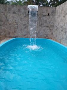 a swimming pool with a waterfall in a brick wall at Casa PARA FINAIS DE SEMANA E TEMPORADA EM UBATUBA in Ubatuba