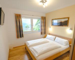 Un dormitorio con una gran cama blanca y una ventana en Haus Wöhrer / Appartement Fischbacher, en Schladming