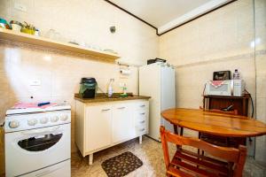 una pequeña cocina con mesa y nevera blanca en Kit Vila Sao Francisco - Localizacao, Seguranca, Conforto e Custo Beneficio, en Campos do Jordão