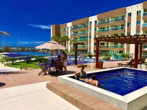 deux personnes assises dans une piscine d'un complexe hôtelier dans l'établissement Vg Fun - Frente Mar! No melhor da praia do futuro, à Aquiraz