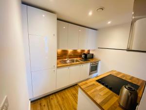 eine Küche mit weißen Schränken und einem Holztisch in der Unterkunft Stewart St James Walk Apartment in Cheltenham