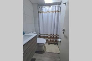 a bathroom with a toilet and a shower curtain at Espectacular departamento con vista al mar en Mirador Barón Valparaíso in Valparaíso