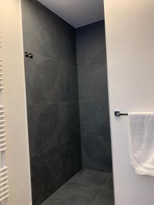 La salle de bains est pourvue d'une douche avec un grand carrelage gris. dans l'établissement Ferienwohnung Geisberg - Moderne Wohnung mit alpinem Flair in Traumlage, à Schönau am Königssee 10 autres photos