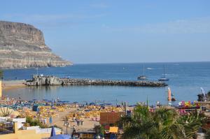 a beach with a bunch of umbrellas and people at HD Mogán Coral Apartments in Puerto de Mogán