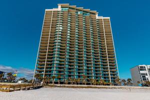a tall building on the beach in front of a building at Phoenix West in Orange Beach