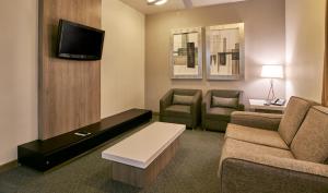 a living room with a couch and two chairs and a tv at Holiday Inn & Suites Chihuahua Expo by IHG in Chihuahua