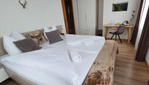 a large white bed in a room with a desk at Hotel Rosengärtli in Leissigen