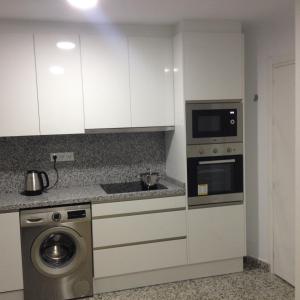 a kitchen with white cabinets and a microwave and a dishwasher at SAN LORENZO STUDIO in Málaga