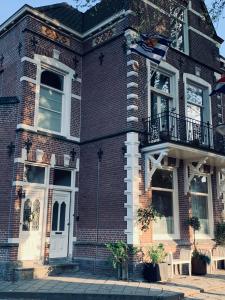 a brick house with a balcony and a flag at B&B Zeeuws genoegen in Vlissingen