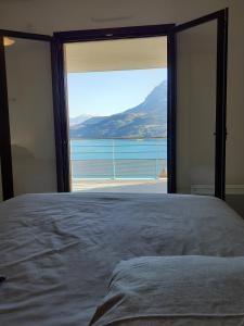 a bedroom with a large window with a view of the water at Vaste appartement 3 chambres - Vue exceptionnelle in Chorges