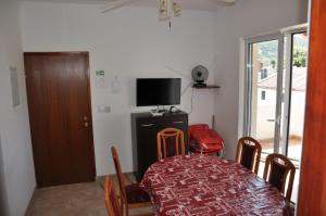 a dining room with a table and chairs and a television at Apartman Somun in Lopar