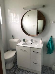 a bathroom with a toilet and a sink and a mirror at Fi's Beach House in Port Macquarie