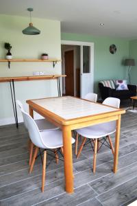a dining room with a wooden table and white chairs at Béal na Banna in Coleraine