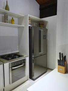 eine Küche mit einem Kühlschrank aus Edelstahl und einem Herd in der Unterkunft Duplex Malawí Muro Alto in Porto De Galinhas