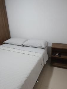 ein Schlafzimmer mit einem Bett und einem Nachttisch daneben in der Unterkunft Duplex Malawí Muro Alto in Porto De Galinhas