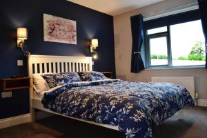 a bedroom with a bed with blue walls and a window at Béal na Banna in Coleraine