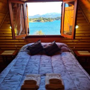 a bed in a room with a large window at Cabañas Aucaman in Villa Pehuenia