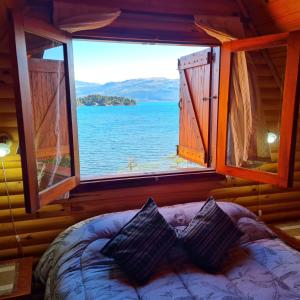 a bedroom with a window with a view of the water at Cabañas Aucaman in Villa Pehuenia