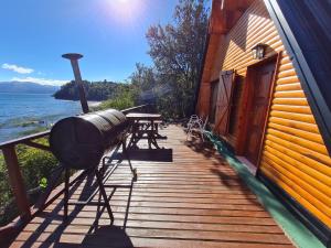 a wooden deck with a grill and a table at Cabañas Aucaman in Villa Pehuenia