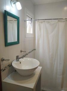 y baño con lavabo y ducha con espejo. en Casa Parque Playa en Necochea