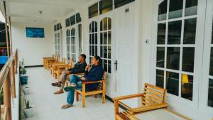 two men sitting in chairs on a porch at Hotel Gunung Mas Syariah in Diyeng