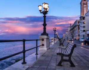 a street light and benches on a sidewalk near the water at Hello Gorgeous Suite Bari in Bari