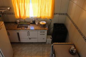 Elle comprend une petite cuisine avec un évier et une fenêtre. dans l'établissement Casa com piscina no litoral norte, à Bertioga